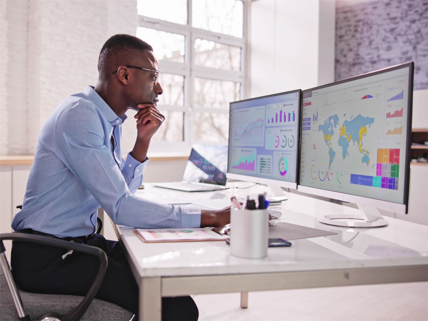 An analyst working with health data dashboards on screen