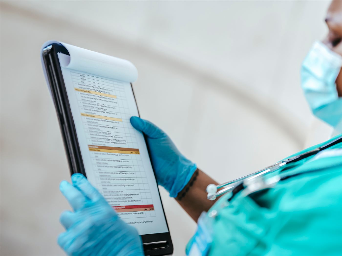 A nurse completing a paper reporting form on a clipboard